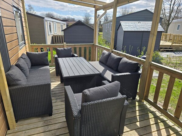 A covered outdoor patio with wicker furniture and a table.