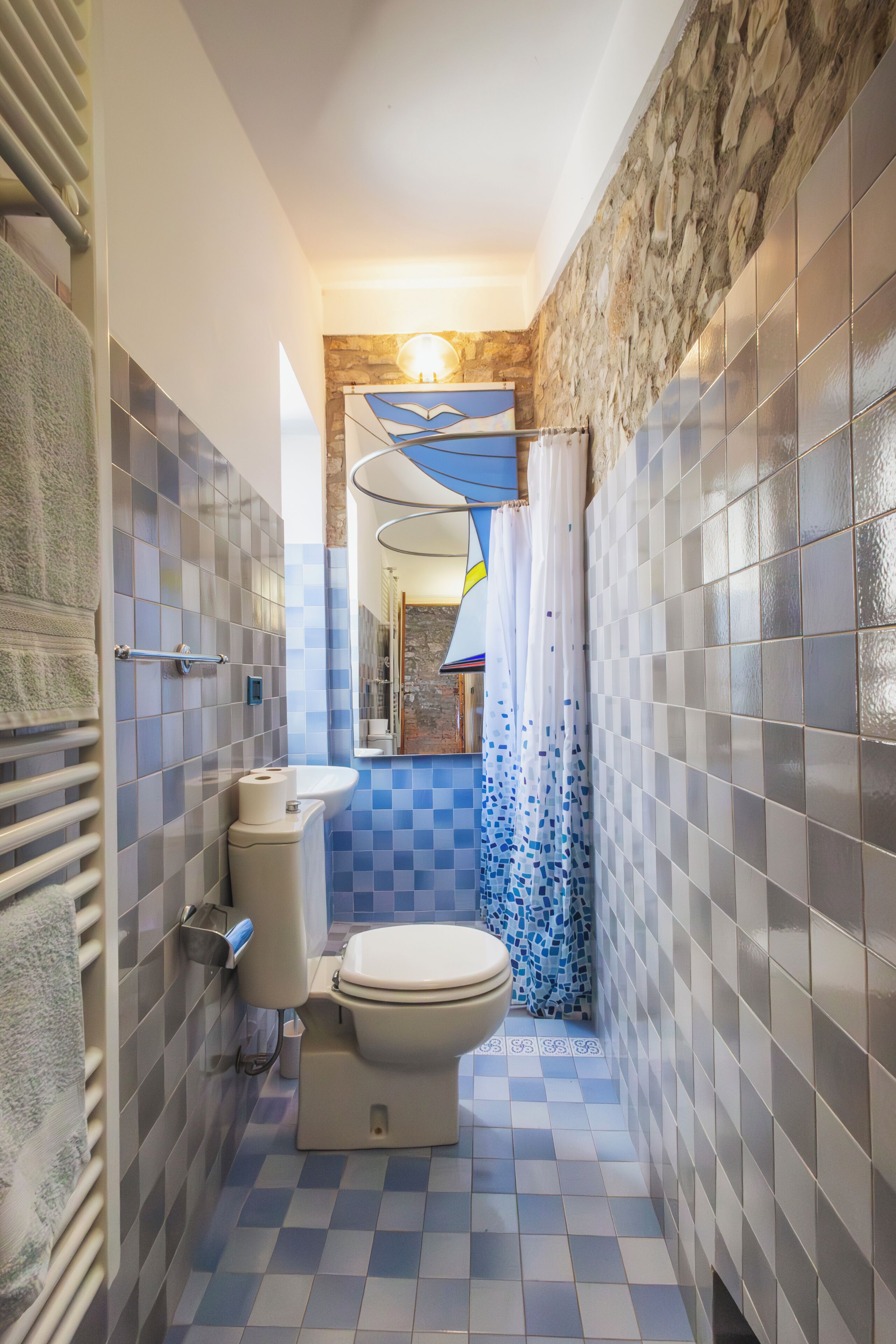 A bathroom with a checkered floor, a toilet, a sink, and a shower area.