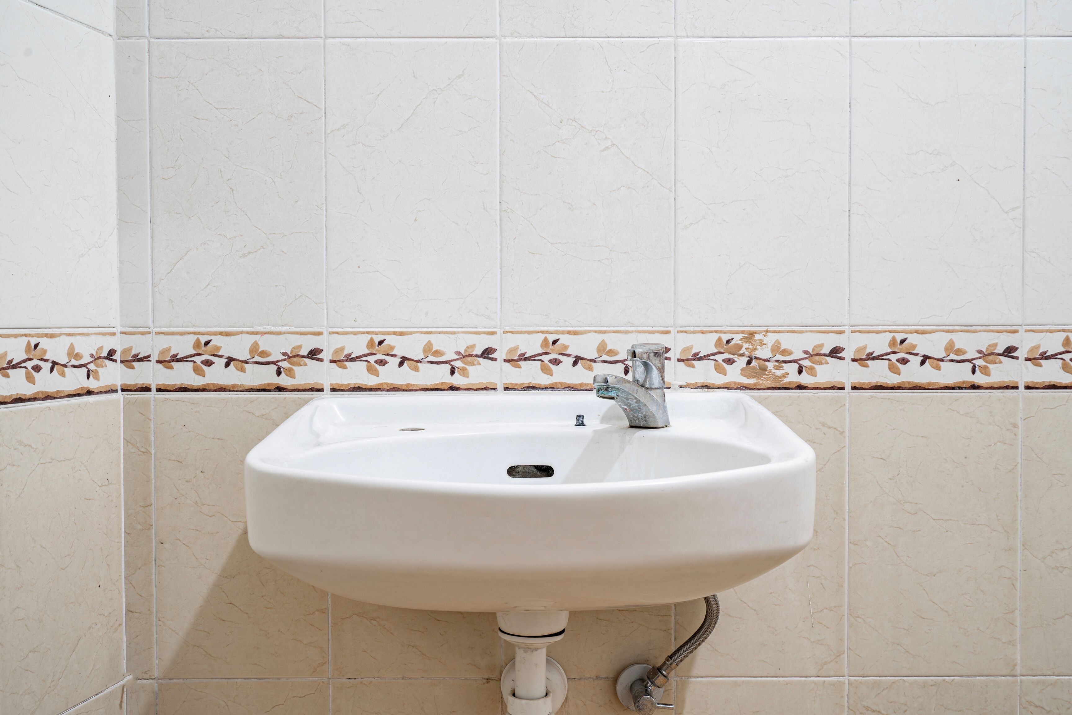 A bathroom sink with a decorative tile border.