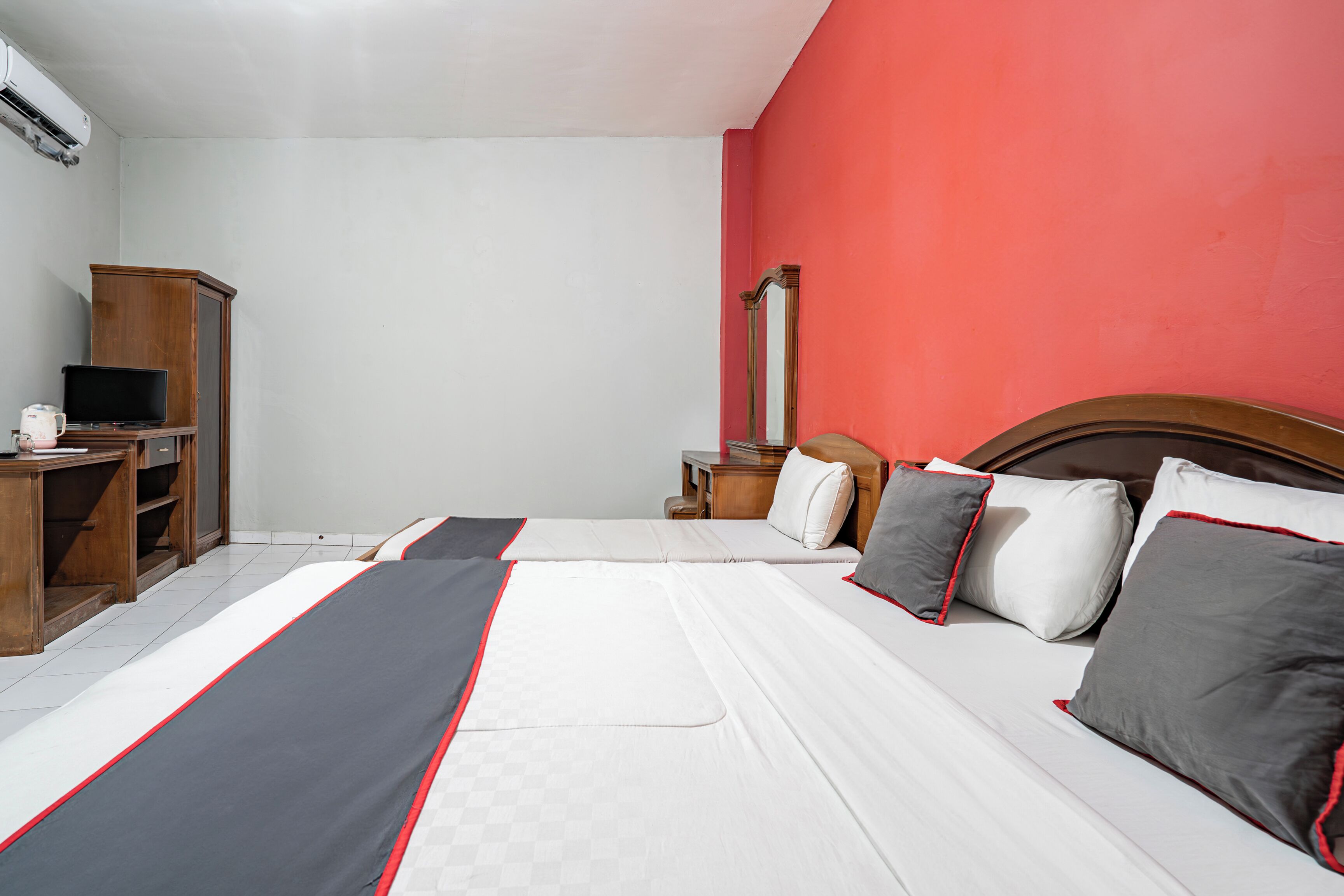 A hotel room with a bed, a desk, a chair, a mirror, and a wardrobe.