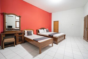 Una habitación con dos camas de madera, un escritorio con una silla, un espejo y una puerta.