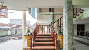 Un escalier avec des balustrades en bois et une colonne en marbre, menant à l’étage supérieur.