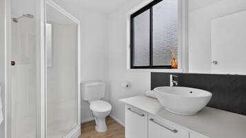 A bathroom with a white toilet, a white sink, and a window with frosted glass.