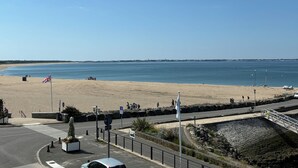 Une plage avec une route, un drapeau et un mur de pierres.
