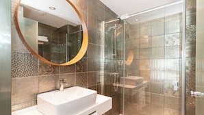 A modern bathroom with a white sink, a large mirror, and a glass-enclosed shower. - Sholeo Lodges Santa Catalina Flats (Las Palmas de Gran Canaria)