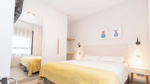 A hotel room with two beds, a mirror, a bedside table, and artwork on the wall. - Sholeo Lodges Santa Catalina Flats (Las Palmas de Gran Canaria)