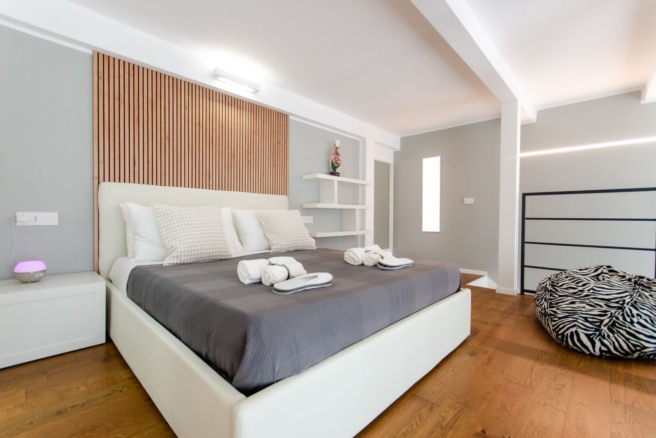 Un dormitorio moderno con una cama, una mesita de noche y un sillón de peluche con estampado de cebra.