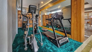 A gym with cardio machines, a treadmill, and a mirrored wall. - Mountain Healing Villa by Nagisa Bali (Baturiti)