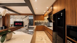 A modern kitchen with wooden cabinets, a marble countertop, and a built-in oven. - Mountain Healing Villa by Nagisa Bali (Baturiti)