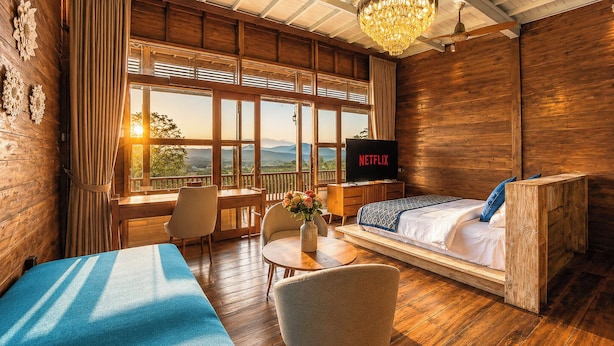 A wooden room with a bed, a desk, a TV, and a view of the outdoors. - Mountain Healing Villa by Nagisa Bali (Baturiti)