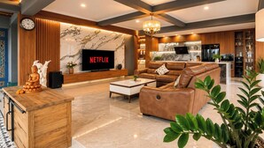 A modern living room with a sofa, a coffee table, a TV, and a Buddha statue. - Mountain Healing Villa by Nagisa Bali (Baturiti)