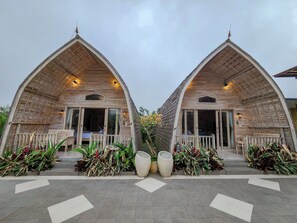 A symmetrical building with a peaked roof and large windows, surrounded by potted plants and a tiled walkway. - Mountain Healing Villa by Nagisa Bali (Baturiti)
