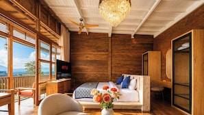 A bedroom with a bed, a TV, a wooden desk, and a balcony. - Mountain Healing Villa by Nagisa Bali (Baturiti)