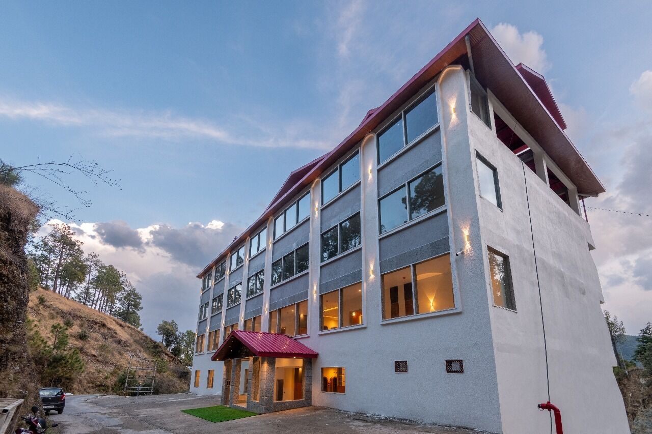 A multi-story hotel with a modern design, featuring large windows and a red roof.