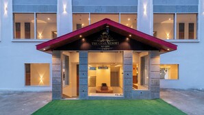 Een hotelentree met een rood dak en een bord waarop 'The Chail Resort' staat.