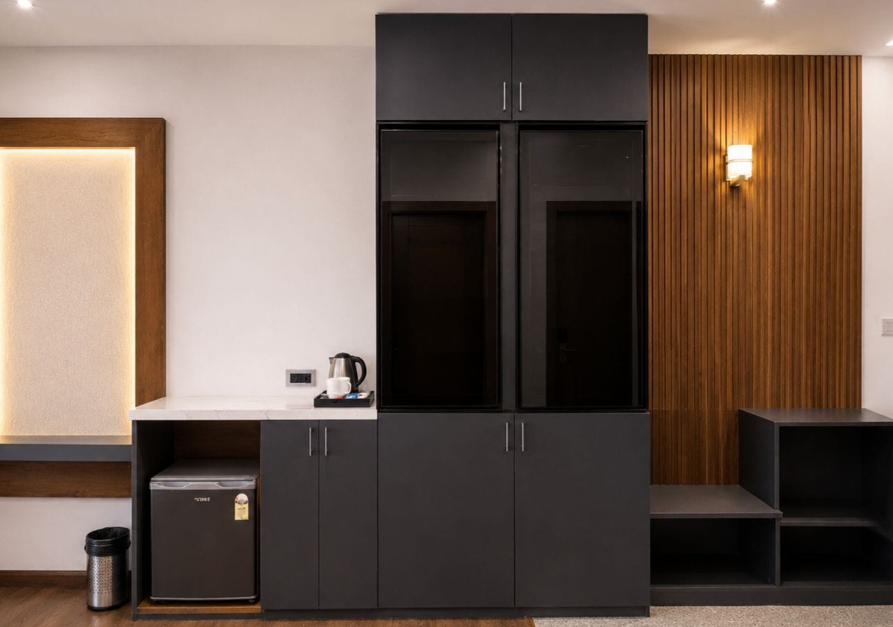 A modern kitchen with a black cabinet, a coffee maker, and a trash can.