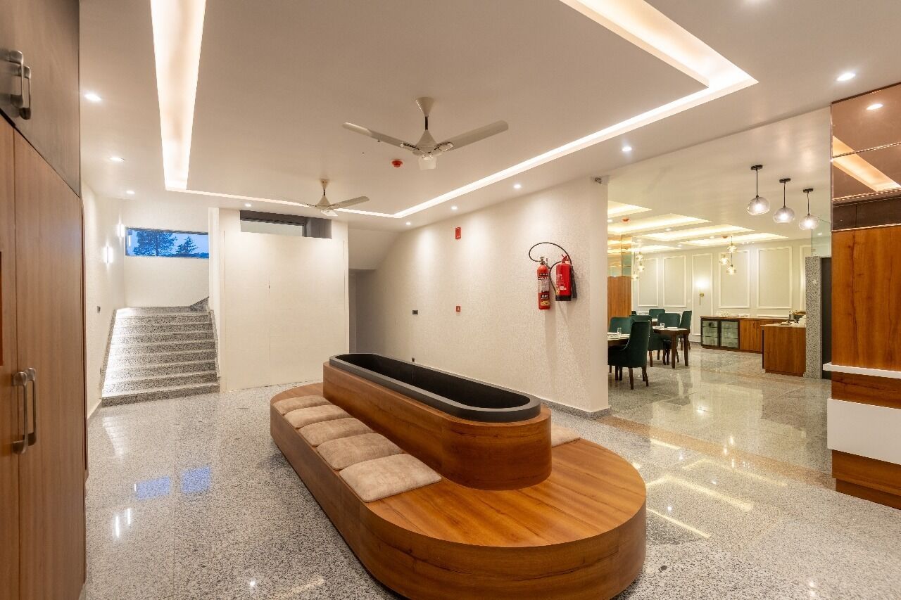 A modern hotel lobby with a central seating area, a staircase, and a reception desk.