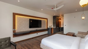 Een moderne hotelkamer met een groot bed, een flatscreen televisie aan de muur, een plafondventilator en een klein zithoekje.