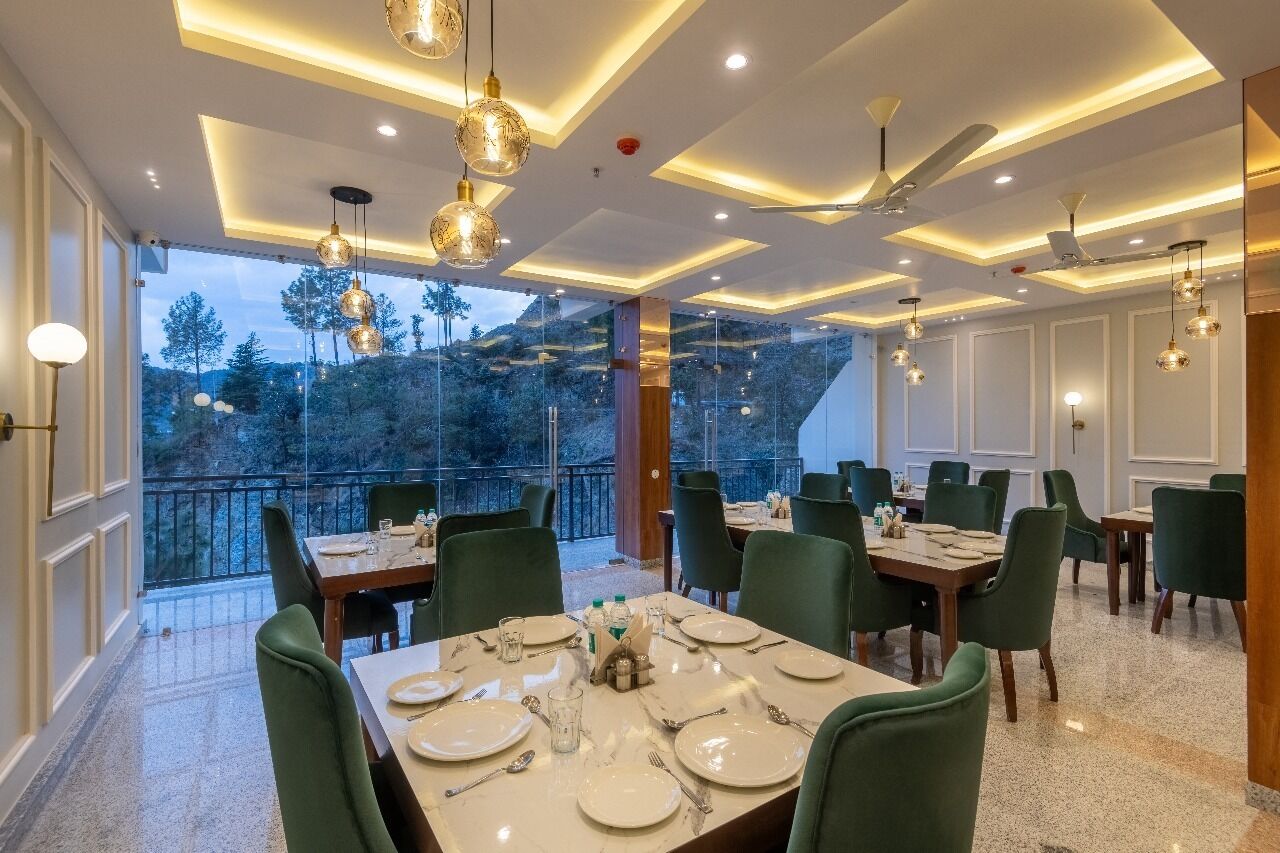 Un comedor con mesas dispuestas para el servicio, amplias ventanas que ofrecen vistas al exterior y ventiladores de techo.