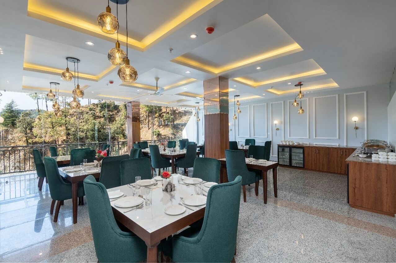 Un restaurante con terraza, sillas tapizadas de verde y una zona de bar.