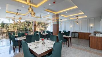 A restaurant with a terrace, green upholstered chairs, and a bar area.