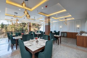 A restaurant with a terrace, green upholstered chairs, and a bar area. - Kavin The Chail Resort - Serene Valley Views (Kandaghat)