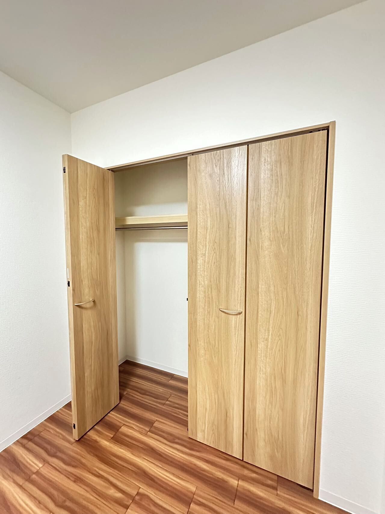 A room with a wooden wardrobe and a wooden floor.