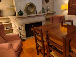 A dining area with a wooden table and chairs, a fireplace, and a stone wall. - 7-bedroom Villa in Pozo Lorente (Pozo-Lorente)
