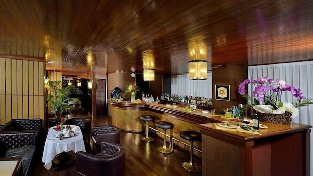 A bar area with leather seating, a bar counter, and decorative plants.