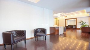 A modern lobby with two leather armchairs, a reception desk, and a large mirror.
