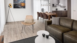 A modern living room with a sofa, a dining area with chairs, a coffee table, and a floor lamp. - Comfortable Villa in Veerse Meer (Wolphaartsdijk)