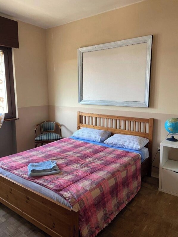 A single bed with a wooden frame and a colorful quilt, a chair, a globe on a small table, and a large framed picture on the wall. - VILLA GIOVANNA (Bergamo)