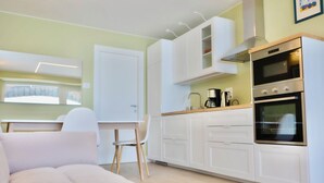 Eine moderne Küche mit weißen Schränken, einem Backofen und einem Essbereich mit weißem Tisch und Stuhl.
