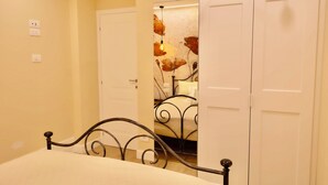 Ein Schlafzimmer mit einem Bett, einem Kleiderschrank und einem Spiegel mit Blumenmuster.