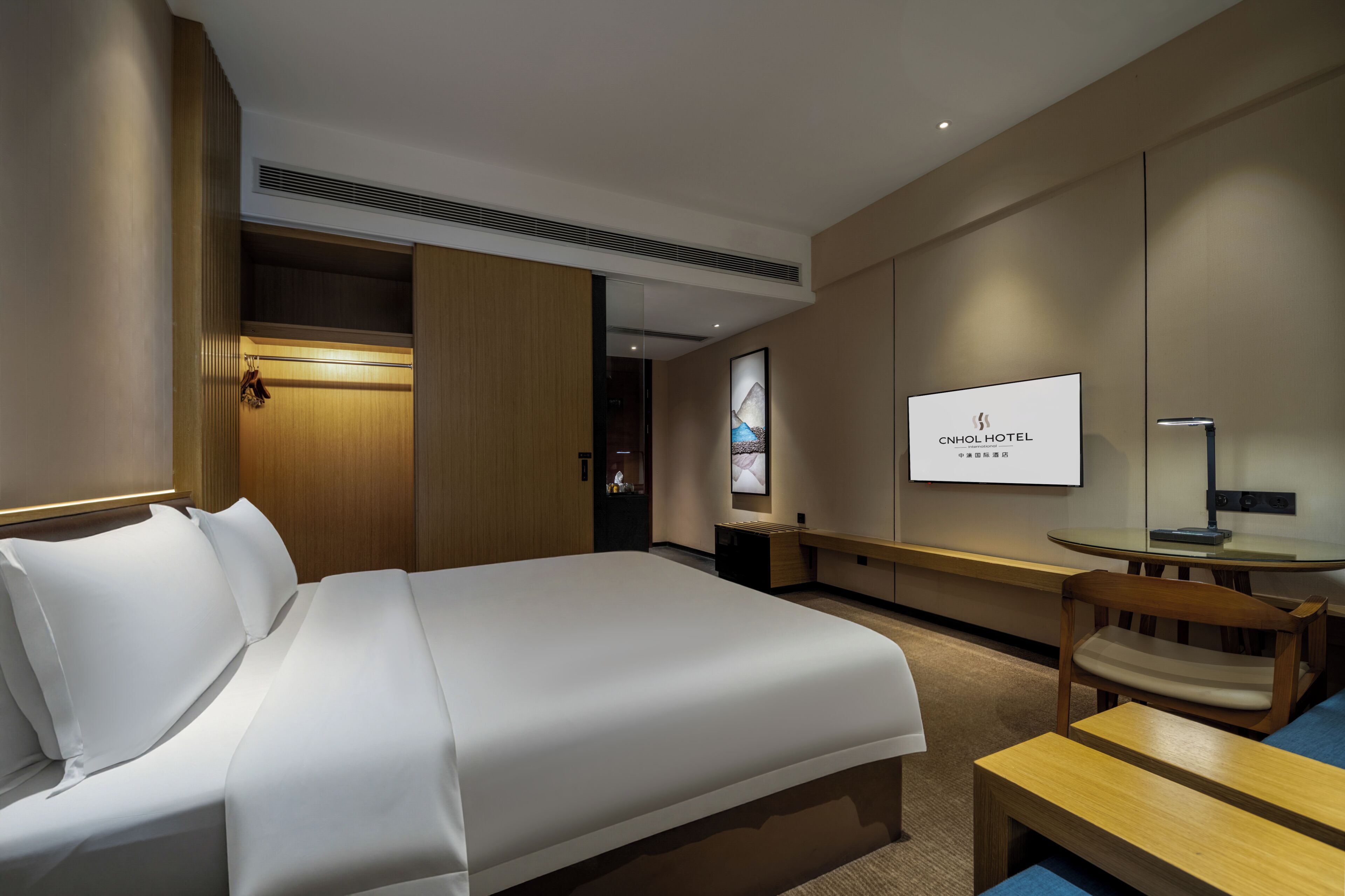 A hotel room with a bed, a TV, a desk, and a chair.