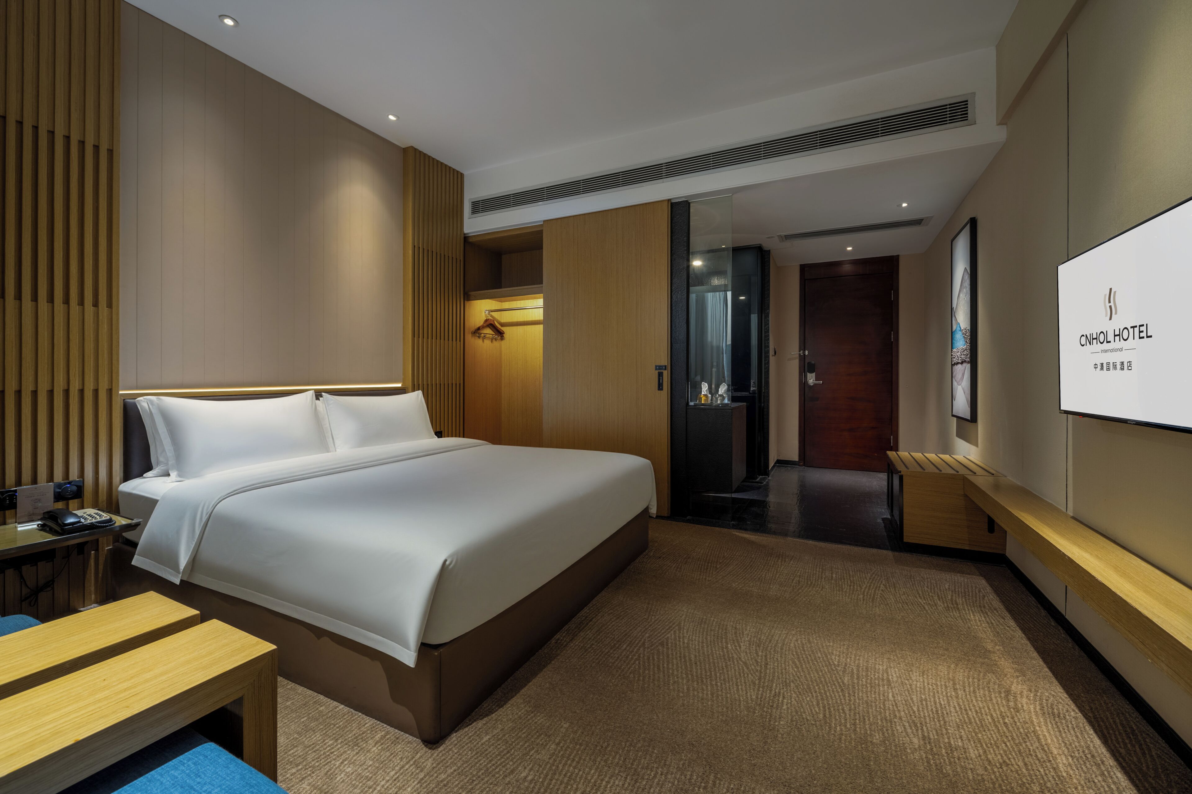 Ein Hotelzimmer mit einem Bett, einem Schreibtisch, einem Stuhl, einem Fernseher und einem Kleiderschrank.