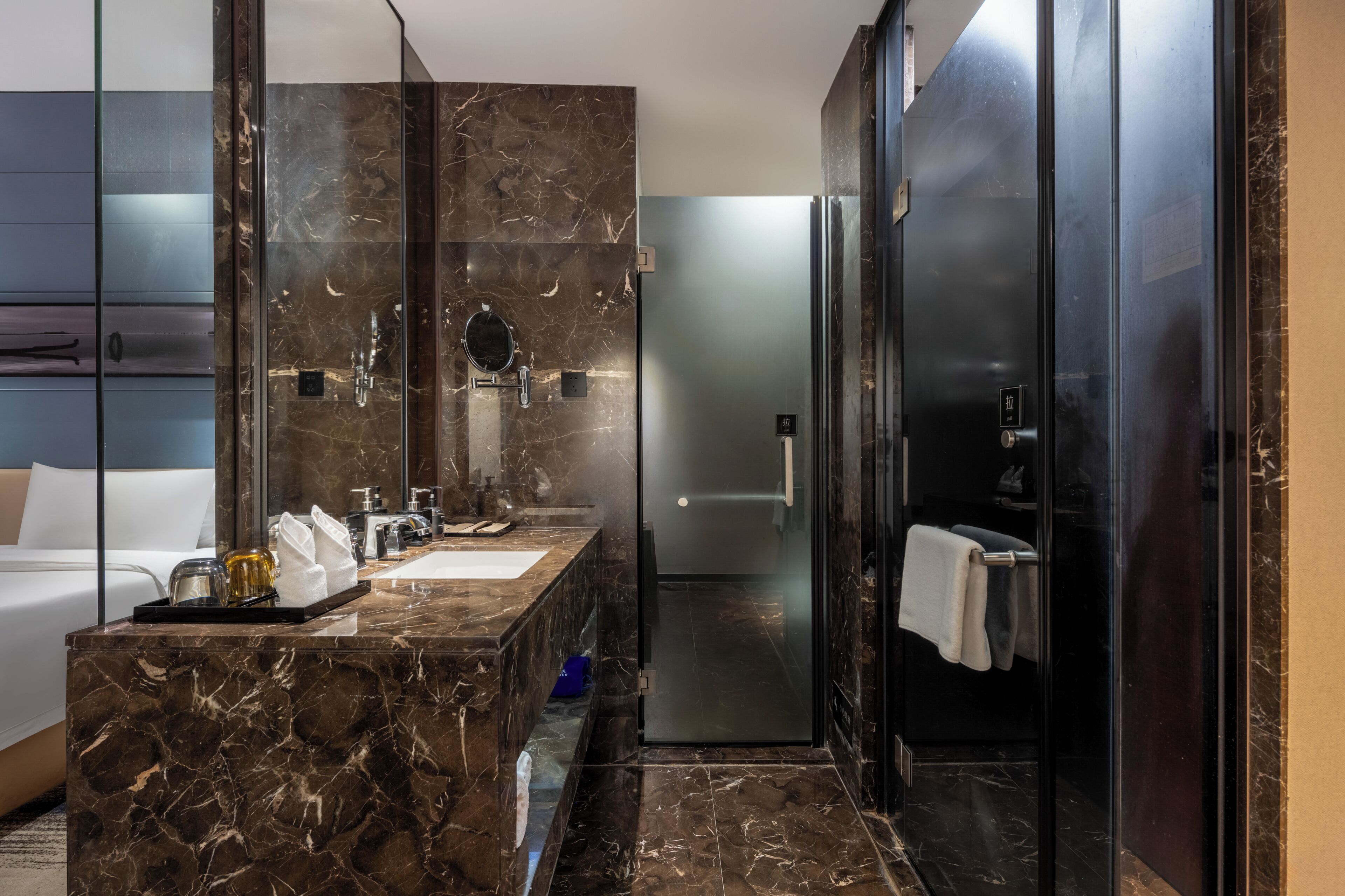Un baño moderno con tocador de mármol, cabina de ducha de vidrio y zona de aseo separada.