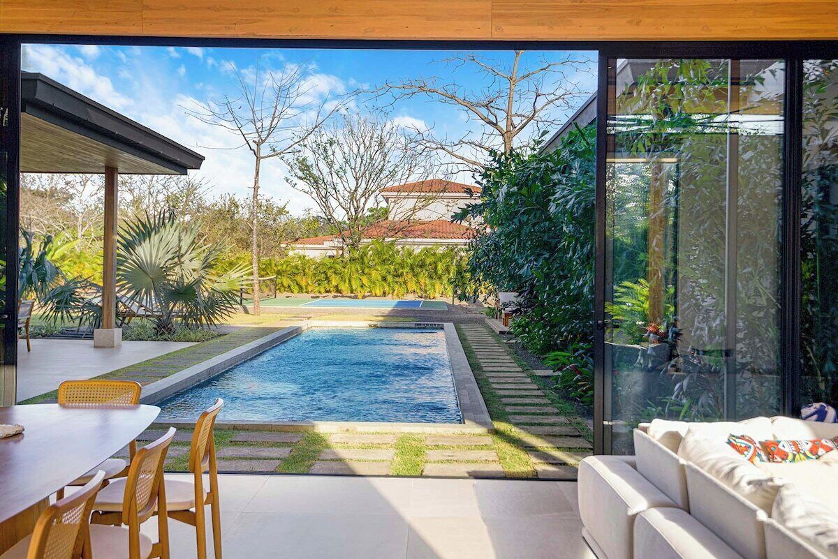 Une terrasse extérieure moderne, dotée d’une piscine, d’un espace salon et offrant une vue sur un quartier résidentiel.