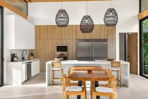 A modern kitchen with a central island, wooden cabinets, and pendant lighting.