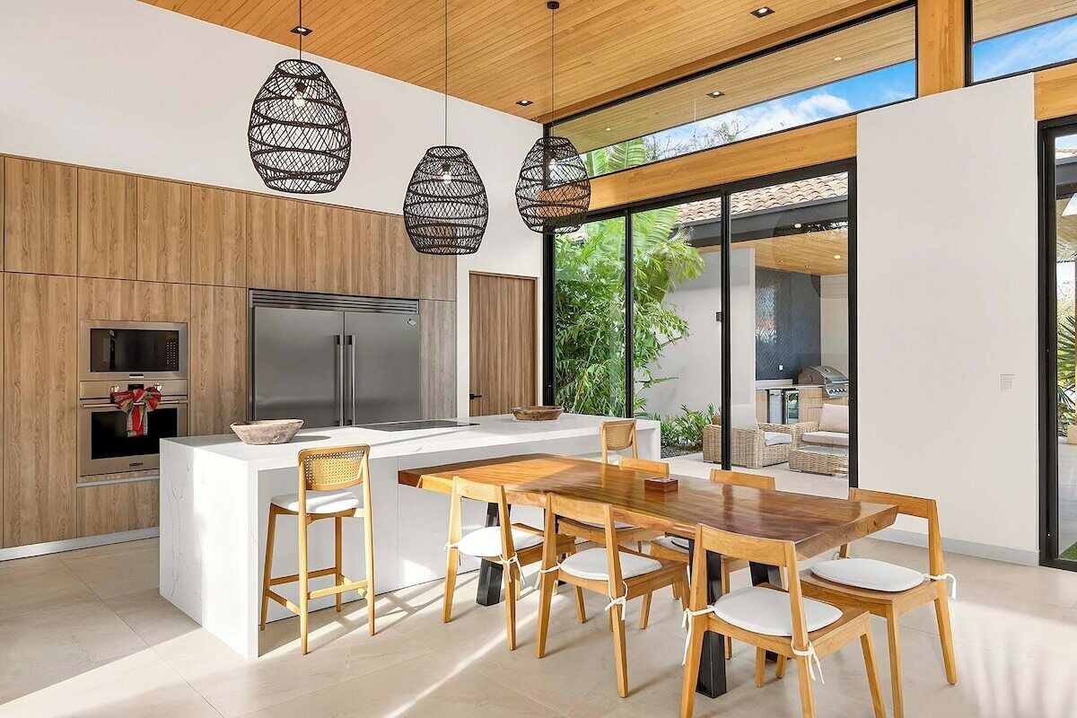 A modern kitchen with a central island, wooden cabinetry, stainless steel appliances, and pendant lighting.