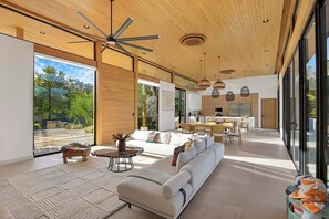 A modern interior with a large sofa, dining area, and kitchen.