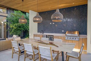 A modern kitchen with a large island, two hanging pendant lights, and a stone backsplash.