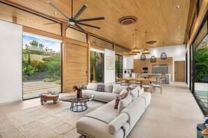 A spacious living area with a large sofa, dining table, and a ceiling fan.