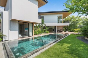 Une maison moderne à deux étages, dotée d’une piscine, d’un espace extérieur aménagé et couvert, et d’une pelouse bien entretenue.