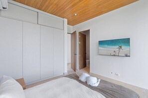 Une chambre à coucher comprenant un lit, une armoire, un tableau et une porte donnant sur une salle de bain.
