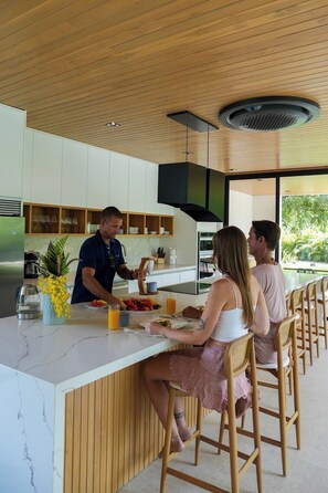 Une cuisine moderne dotée d’un îlot central, de meubles en bois et offrant une vue sur la verdure environnante.