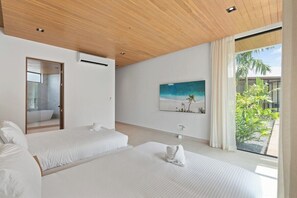 Une chambre d’hôtel moderne avec deux lits, une grande fenêtre donnant sur un paysage verdoyant et un tableau accroché au mur.