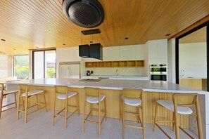 Une cuisine moderne avec un îlot central, des tabourets de bar et une grande fenêtre.