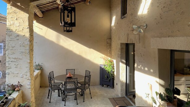 A covered patio with a round table and chairs, a hanging light fixture, and potted plants. - Logis de Charlise (Vallabrix)