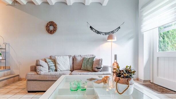 Una sala moderna con un sofá, una mesa de centro de vidrio y un estandarte decorativo.